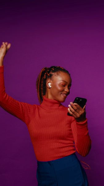 Young woman dances and enjoys music on her phone in a vibrant studio