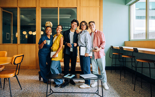 Group of young adults posing together in a casual office environment