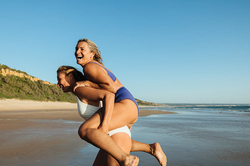 Two joyful mature women enjoying a playful moment at the beach