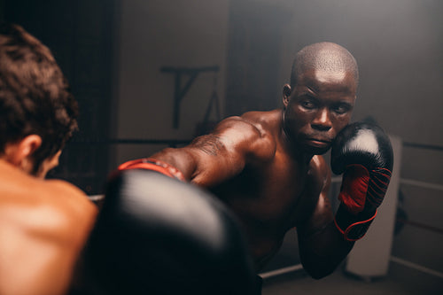Black boxer at striking his opponent during a match