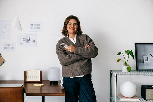 Office confidence surrounds the woman as she smiles with a smartphone at her workspace