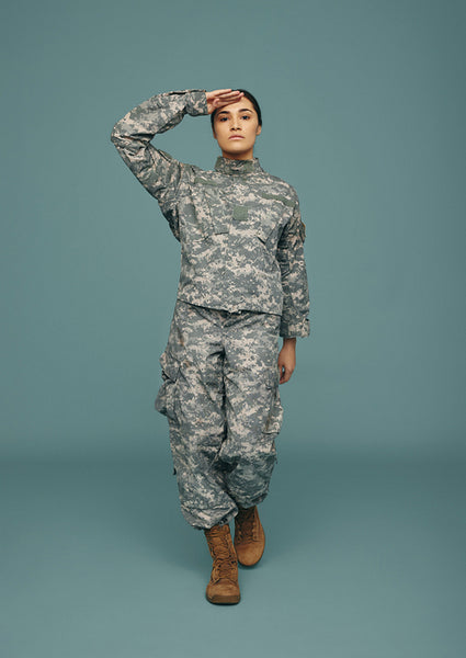 Female army soldier saluting in a studio