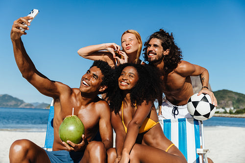 Group of friends taking a selfie at the beach during summer holiday