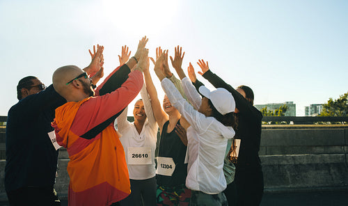 Diverse group of runners celebrate with a joyful high five