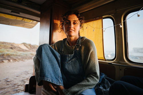 A woman sits in a retro van looking at the camera