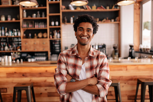 Handsome young man with his arms crossed in a cafe