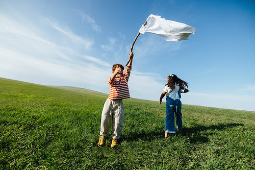 Kids waving white flag symbolizing peace in open field