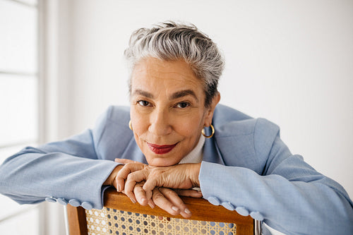 Top female professional sitting on a chair in her office, dressed in a sharp suit
