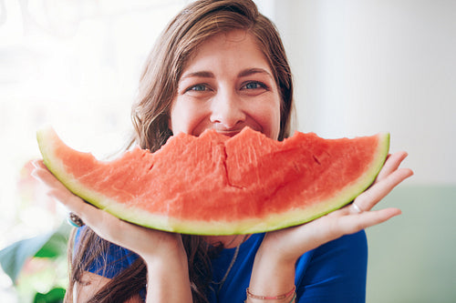 Happy young woman holding a slice of watermelon