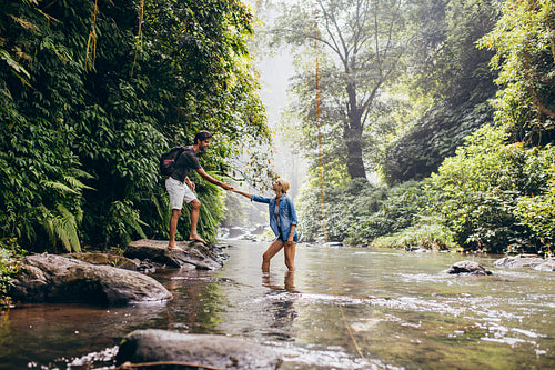 Young couple walking across stream