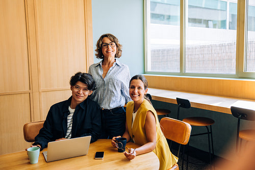 Three coworkers enjoying a casual meeting in a well-lit modern workspace