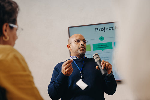 Businessman presenting project scope using a microphone during a formal meeting