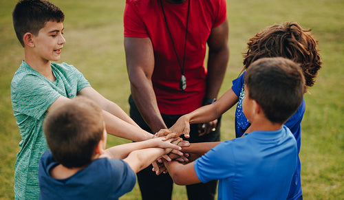 Coach and students putting their hands together in a huddle
