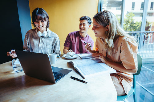 Friends preparing for exams in a modern study space with laptops and books, promoting teamwork and academic success