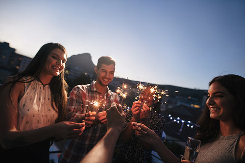 Friends enjoying rooftop party with sparklers