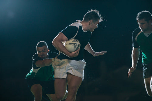 Rugby player running with ball and tackling