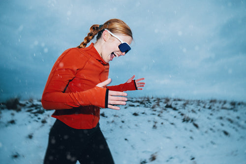 Portrait of a woman outdoors in winter snow with sunglasses and sportswear