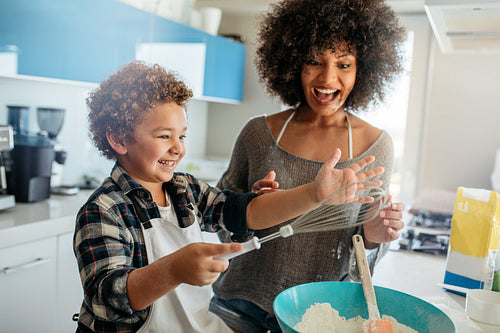 Mother and kid having fun in kitchen making a batter