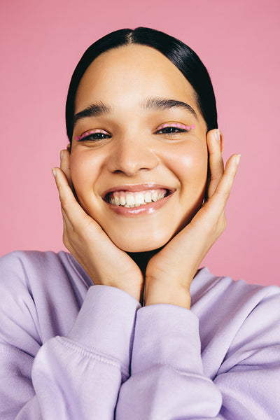 Self-love and self-care: Portrait of a woman smiling and giving her face a warm embrace