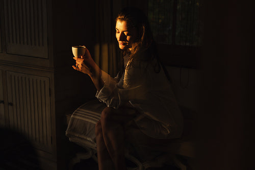 Brunette woman having coffee in the dark