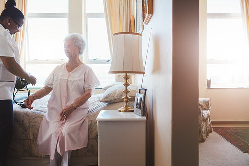 Nurse measuring blood pressure of senior woman