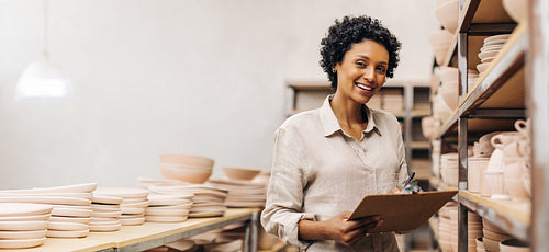 Successful female ceramist smiling at the camera in her store