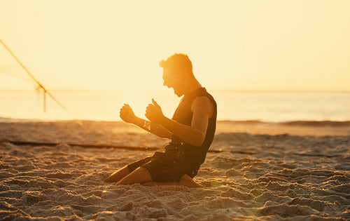 Australian beach volleyball player celebrating victory at sunset with teammates on sandy court