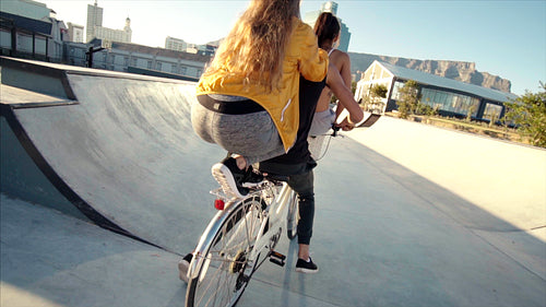 Group of playful friends riding a bike together in a skate park