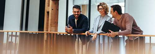 Creative design team stands on an interior balcony discussing business ideas