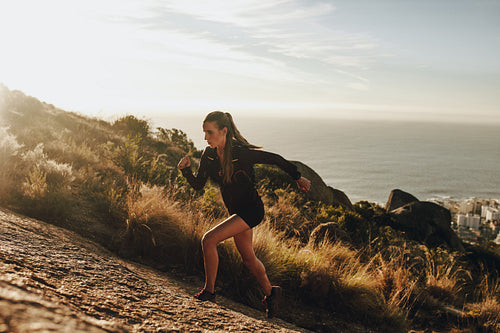 Fit woman running up a rocky mountain trail