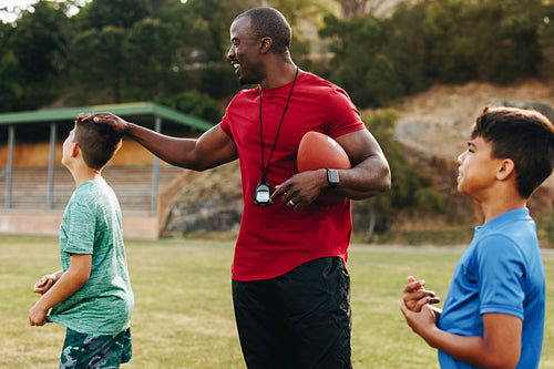 Elementary school coach playing with his students in a rugby field