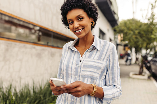 Happy young woman using a smartphone outdoors