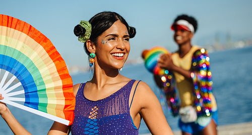 Woman leads carnival fun with rainbow fan at beach