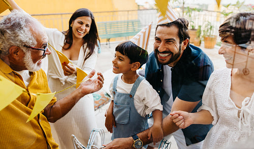 Family celebrating a birthday with festive decorations and joyful laughter outdoors