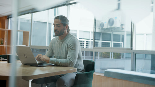 Business man using a laptop for a virtual meeting, communicating with his colleagues from a coworking space