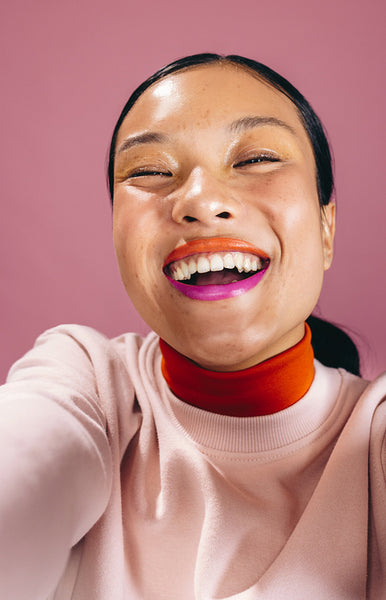 Happy selfie with two toned lips, woman taking a self-portrait in a studio