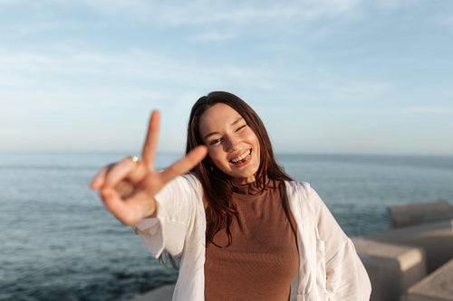 Playful young woman showing the peace sign outdoors