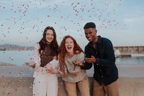 Friends celebrating with red and white confetti outdoors