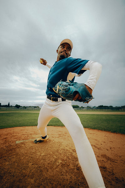 Powerful male baseball player in action throwing a pitch on the field with a glove