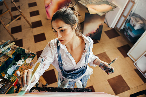 Creative young artist painting with a paintbrush in her studio