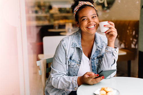 Cheerful woman smiling and using her tablet pc in cafe