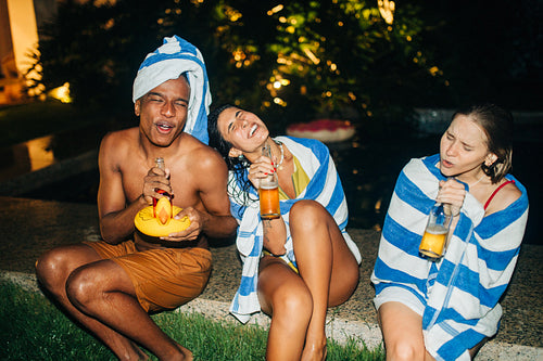 Friends enjoy a night by the pool with drinks