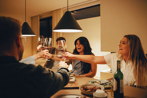 Friends enjoying wine and dining in a cozy home with laughter and cheer