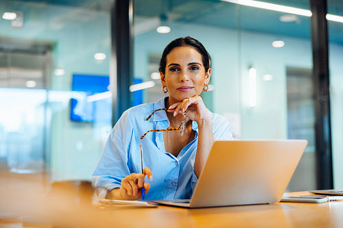 Professional woman sitting at desk with laptop in a bright office setting