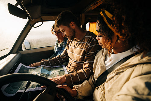 Family road trip: Friends reading map in a van