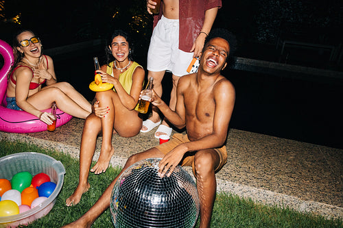 Friends pool party night with disco ball and drinks