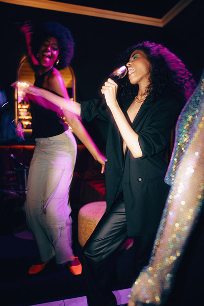 Friends singing karaoke together at a lively party in vibrant lighting