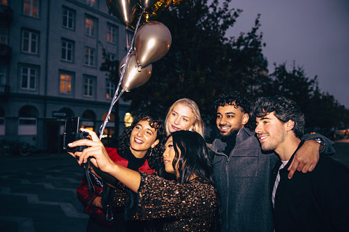 Friends capturing memories at night with laughter and golden balloons
