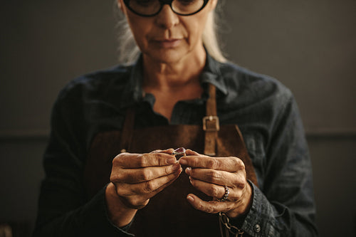 Woman goldsmith inspecting silver ring