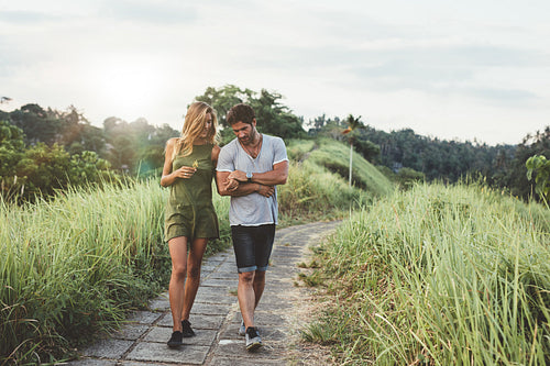 Young couple walking through pathway in rural field